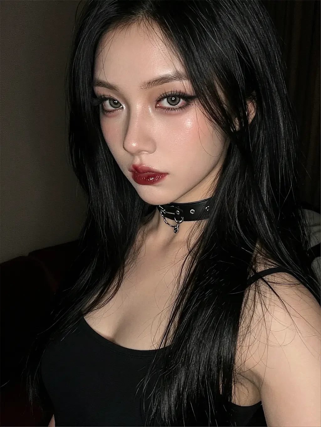 Selene — close portrait of a dark-haired woman in a black top and choker, red lips, looking straight into the camera